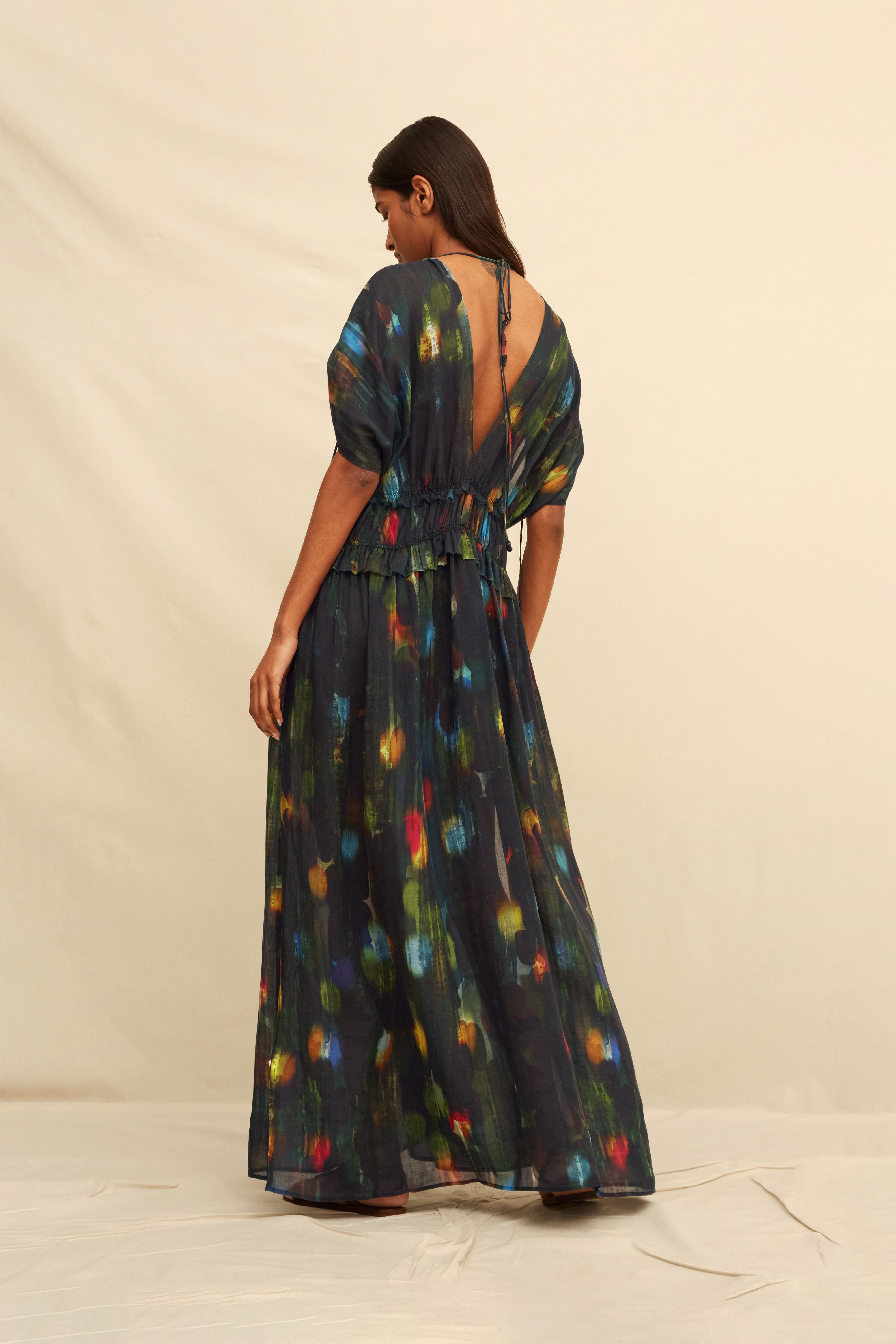Woman wearing a long black dress with abstract painterly pattern on a beige background