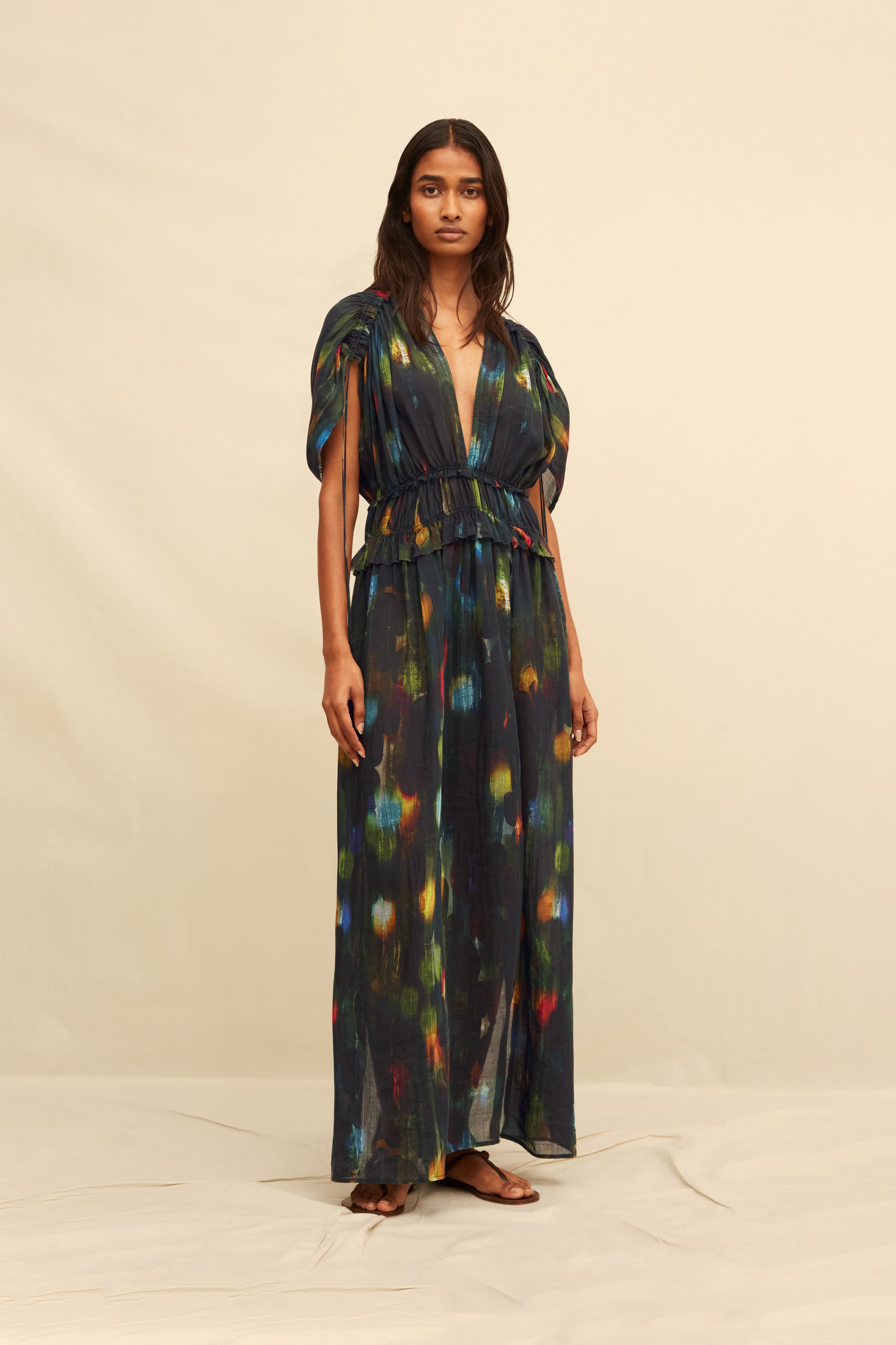 Woman wearing a long black dress with abstract painterly pattern on a beige background