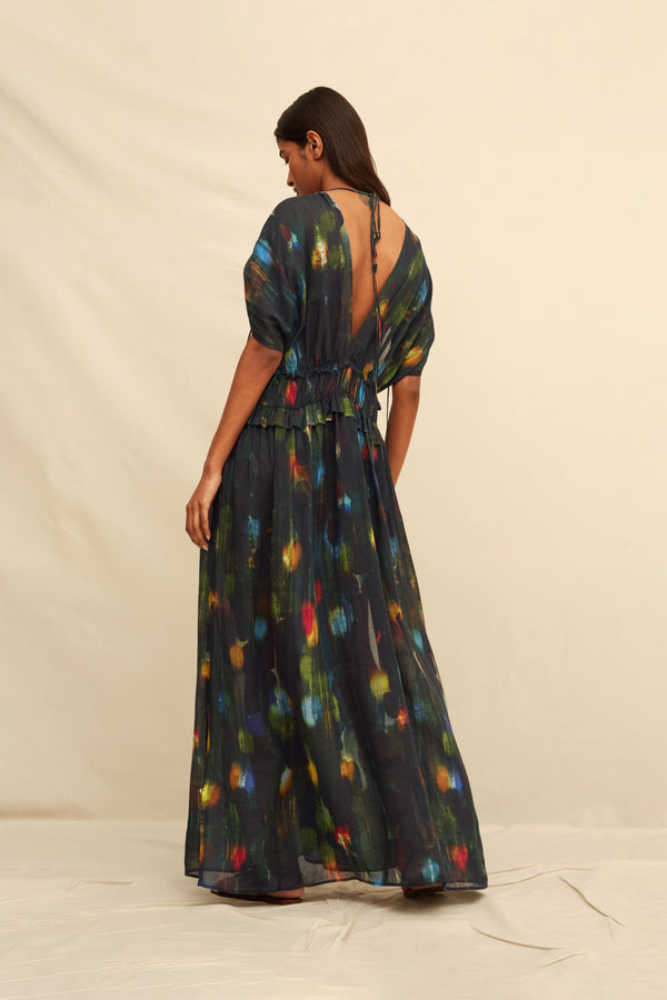 Woman wearing a  long black dress with abstract painterly pattern on a beige background