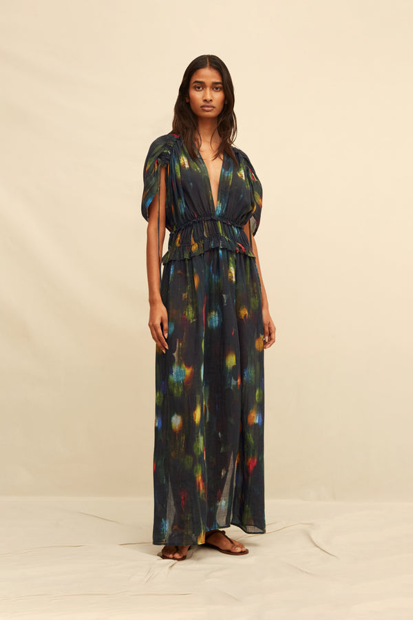 Woman wearing a  long black dress with abstract painterly pattern on a beige background