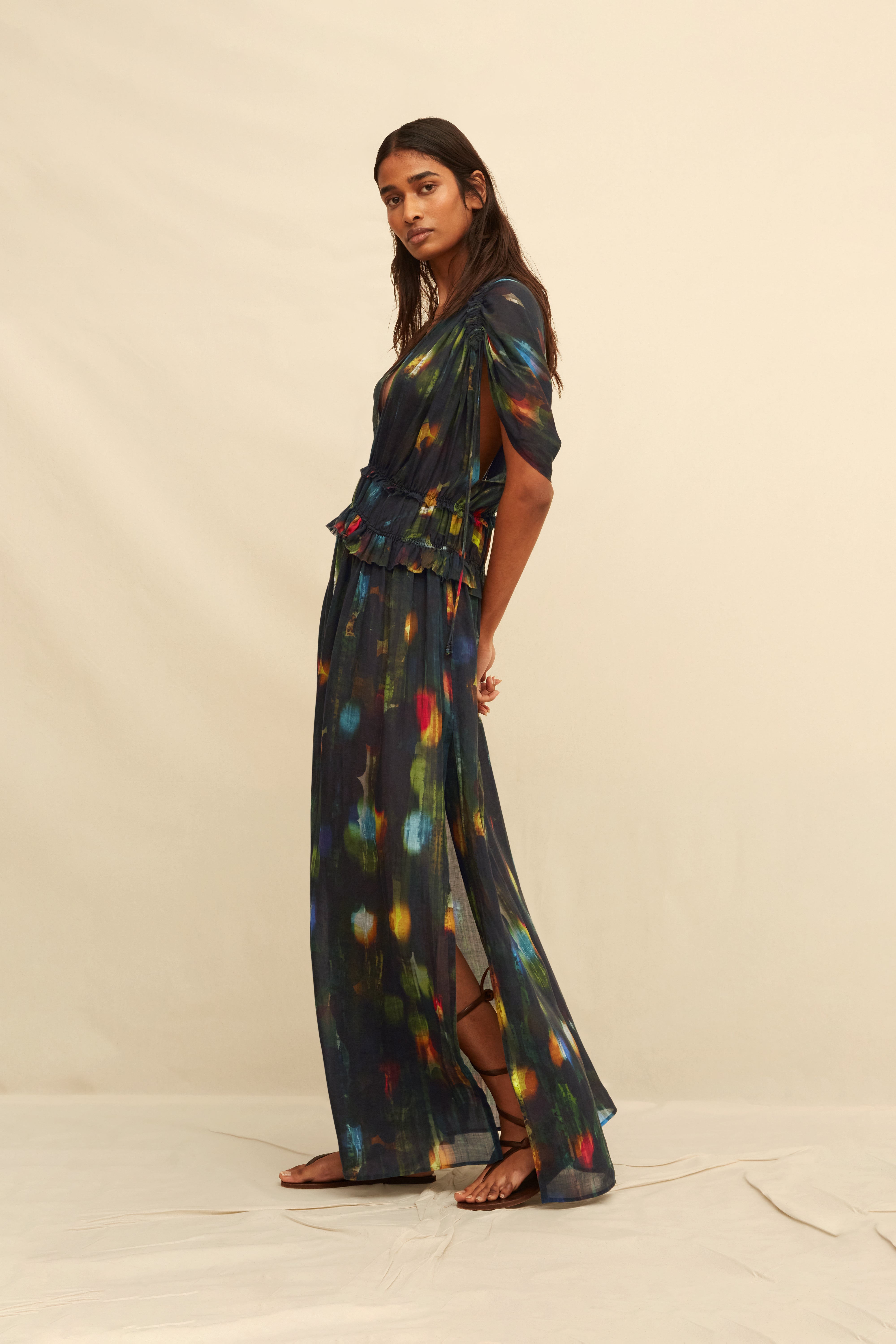 Woman wearing a  long black dress with abstract painterly pattern on a beige background