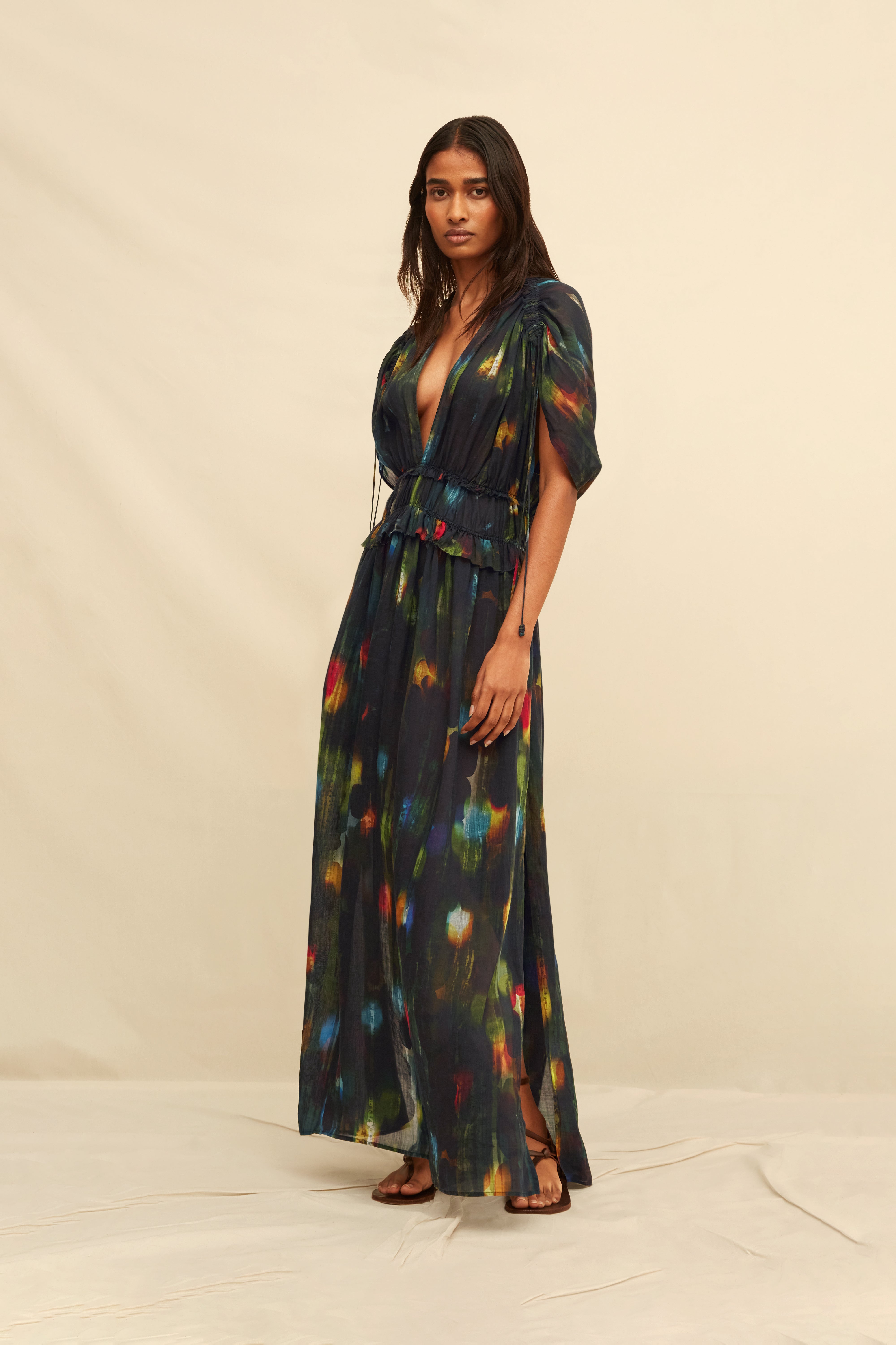 Woman wearing a  long black dress with abstract painterly pattern on a beige background