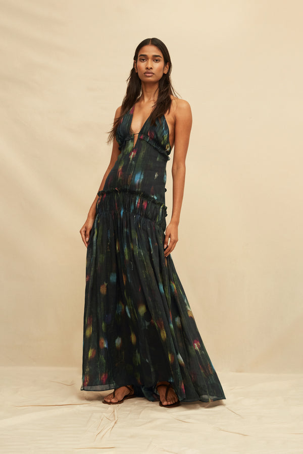 Woman wearing a long, dark painterly printed dress against a beige background